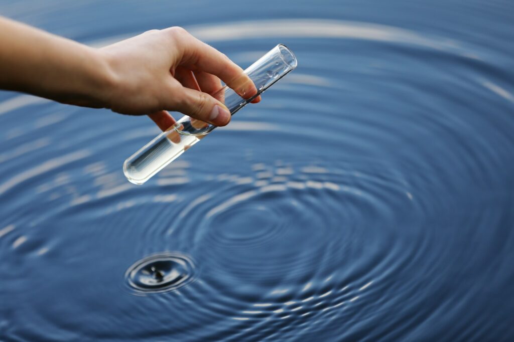 Water sample. Hand collects water to explore. Concept - water purity analysis, environment, ecology