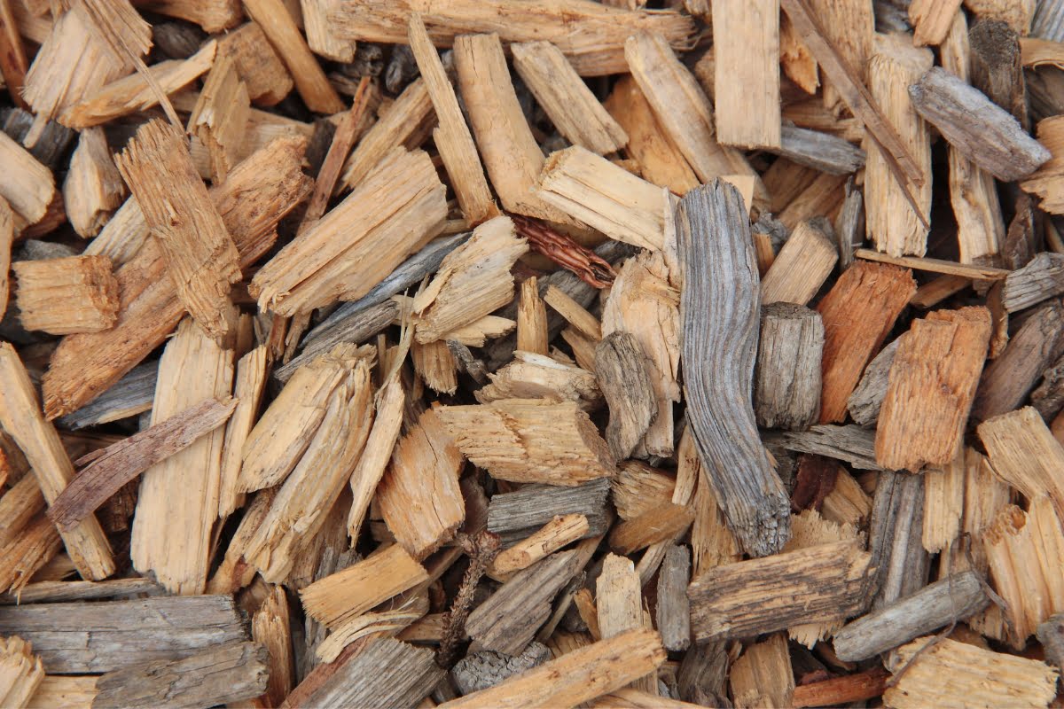 A close-up image of wood chipping reveals an intricate pattern of wood chips in various shades of brown and gray.