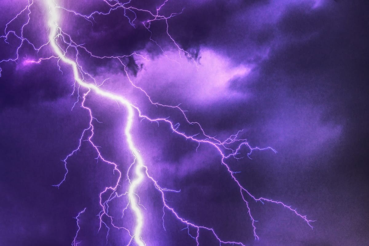 A purple lightning bolt branches across a cloudy night sky, echoing the fierce energy often seen during Georgia storm damage.