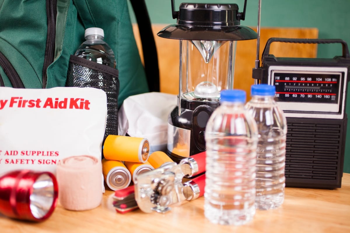 Amidst the Georgia storm damage, emergency supplies like a first aid kit, bottled water, flashlight, lantern, radio, batteries, and rope are meticulously displayed on a table.