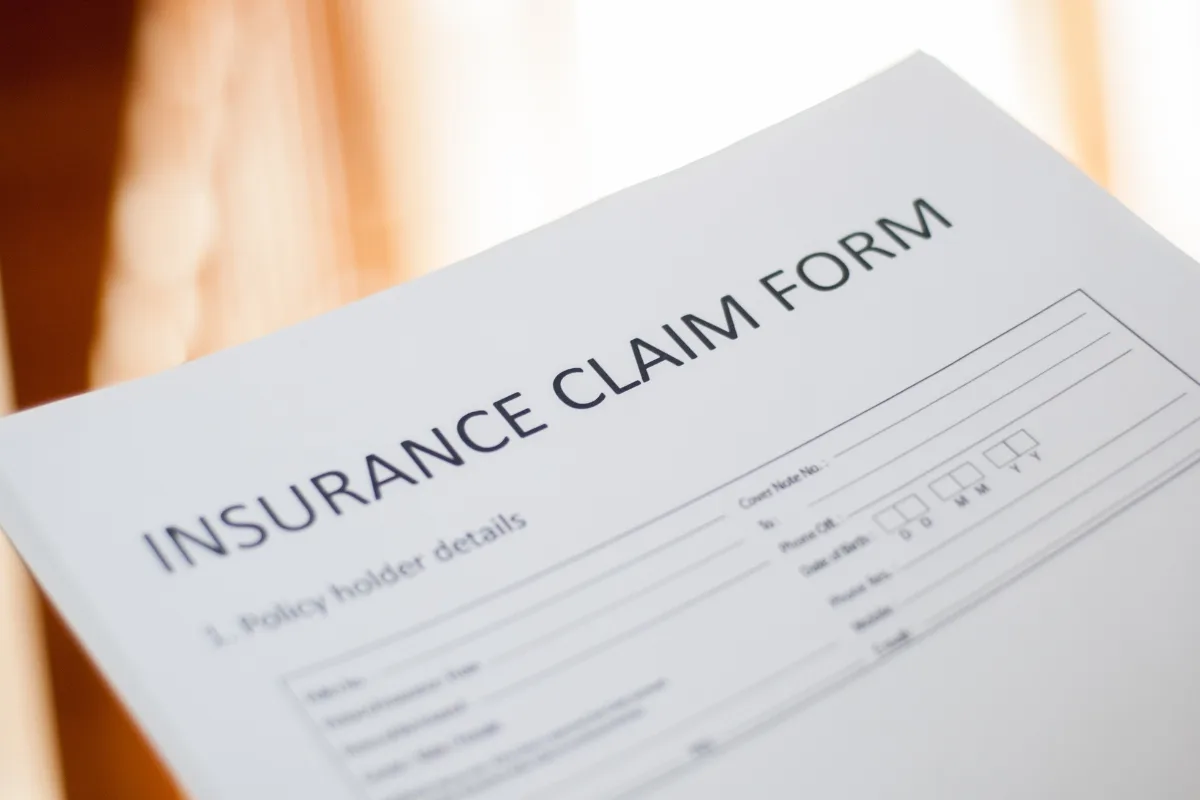 Close-up of a storm damage insurance claim form, highlighting sections for policyholder details and contact information.