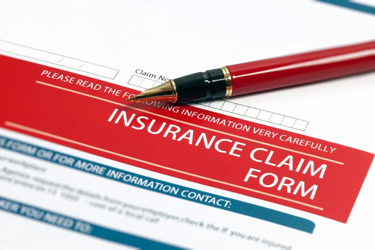 A red pen rests on a storm damage insurance claim form with highlighted text in bold.