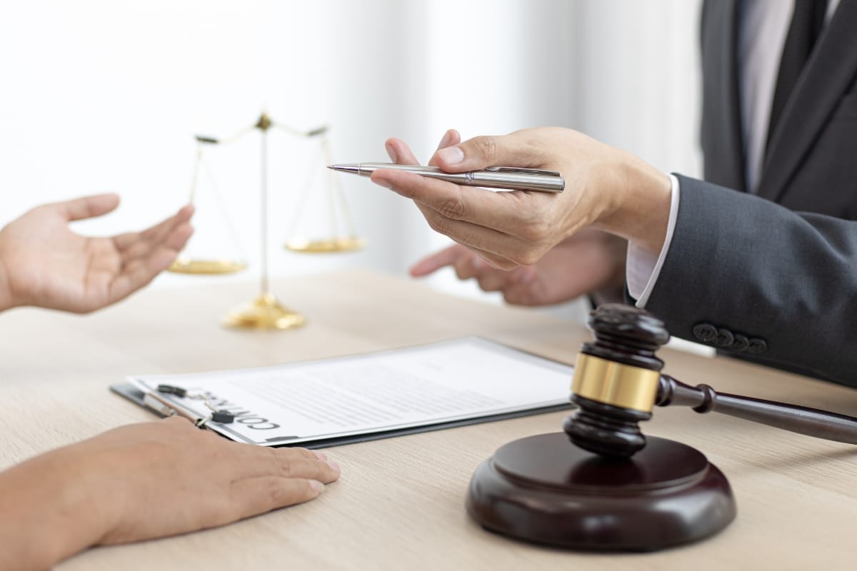 Two people discussing a legal document with a gavel and scales of justice in the background, as they examine storm damage insurance claims.